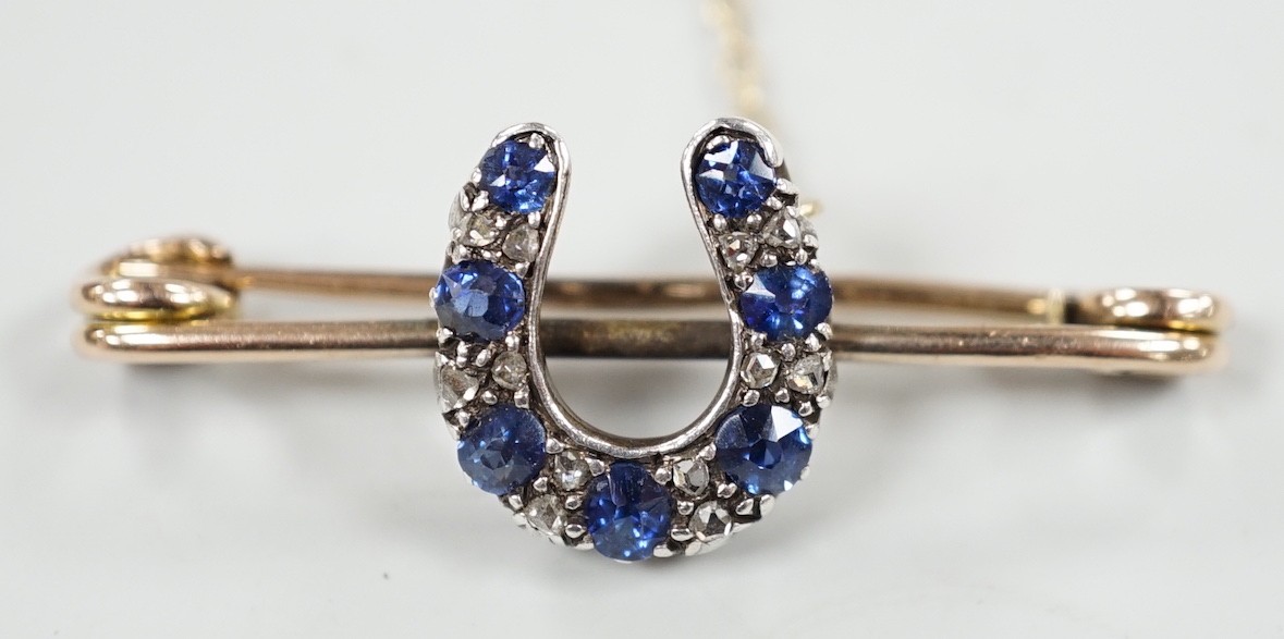 A late Victorian yellow metal. sapphire and diamond cluster set horseshoe bar brooch, 42mm, gross weight 5.3 grams.